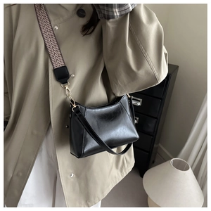 Détail du sac à bandoulière en cuir noir avec large sangle tissée géométrique et ferrures dorées