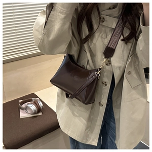 Detail der dunkelbraunen Hobo-Tasche aus Leder mit gestreiftem Gurt und glänzendem Finish