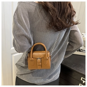 Detailed side view of a brown leather crossbody bag with silver chain strap on a model