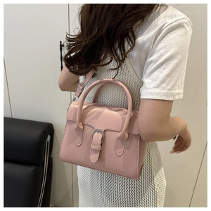Side view of pink leather crossbody bag shown on model with adjustable shoulder strap