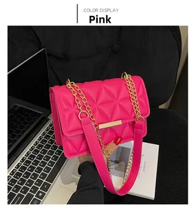 Dettaglio della borsa rosa trapuntata con tracolla a catena dorata su scrivania scura