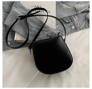 Detail of a vintage black saddle bag with silver hardware on an artistic book background