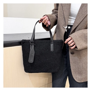 Detail of black faux shearling tote bag with leather handles and fashion letter tag