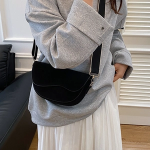 Sac selle demi-lune noir tendance avec large bandoulière porté sur une tenue décontractée