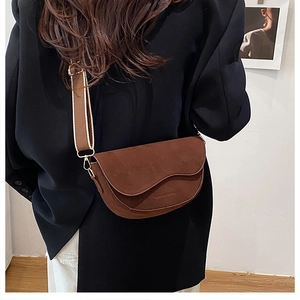 Détail du sac besace en daim marron avec large bandoulière et finitions dorées chic