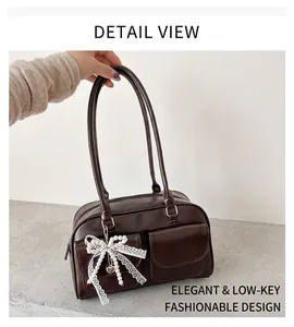 Détail du sac Boston marron foncé avec deux poches à rabat et breloque en dentelle