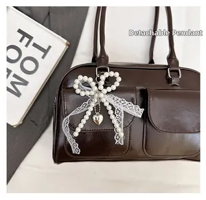Détail du sac marron café avec nœud en dentelle perlé amovible et pendentif cœur