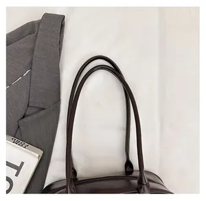 Détail du sac à main en cuir marron foncé avec doubles anses et texture huilée