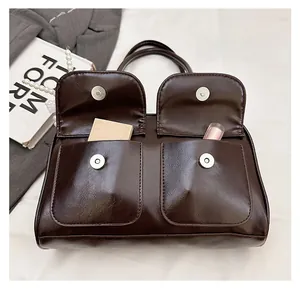 Détail du sac à main marron brillant montrant les deux poches avant à boucle magnétique