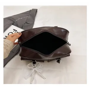 Vue macro du sac Boston en cuir PU marron foncé avec intérieur spacieux et nœud en perles