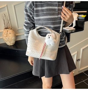 Detail of white woven PU leather handbag with adjustable strap and cute plush dog pendant