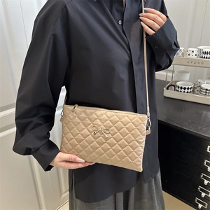 Minimalist beige quilted square crossbody bag with gold bow clasp and thin strap