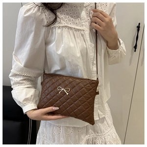 Close-up of brown quilted crossbody bag with a delicate gold bow metal buckle detail