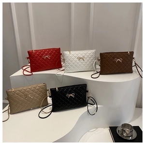 Multiple colors of quilted crossbody bags with golden metal bow accents on a display stand