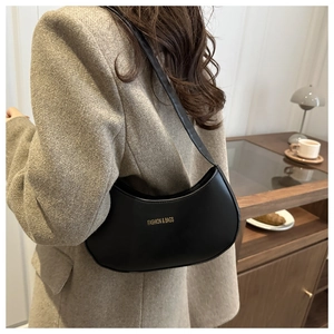 Detail of a black crescent moon shoulder bag with gold FASHION & BAGS lettering print