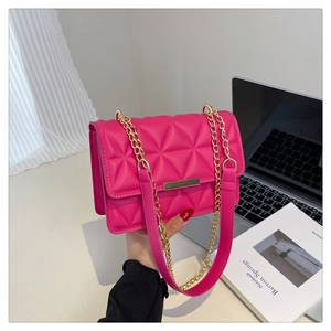 Detail of rose red quilted crossbody bag with gold metal trim and chain strap