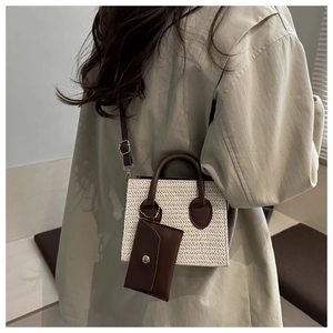 Detail of cream woven small square bag with brown handles shown on a model
