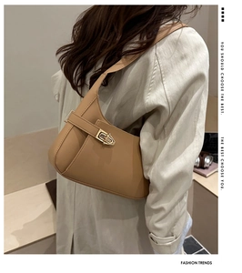 Detail of camel crescent shoulder bag featuring matte leather and a gold metallic clasp