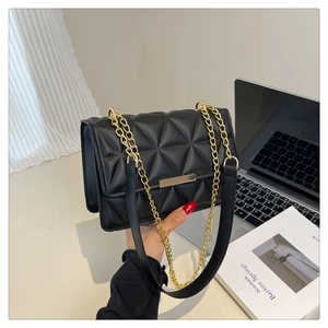 Detailed view of the black quilted crossbody bag with gold chain strap and metal clasp