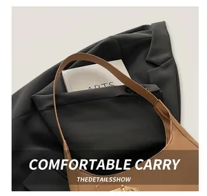 Close-up of a brown leather shoulder bag with a gold buckle paired with a black blazer