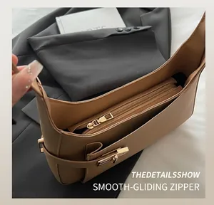 Detail shot of the smooth metal zipper and internal storage of the tan shoulder bag