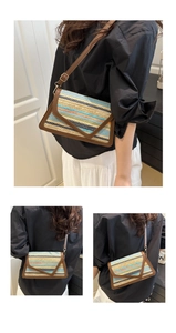 Detail of colorful striped straw crossbody bag with brown leather trim and metal buckles