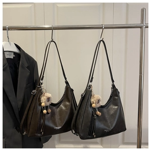 Detail view of large matte leather hobo bag with fashion logo and plush lamb charm