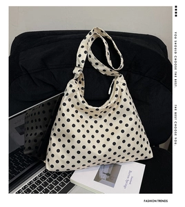 Sac à bandoulière à pois présenté avec style à côté d'un ordinateur portable