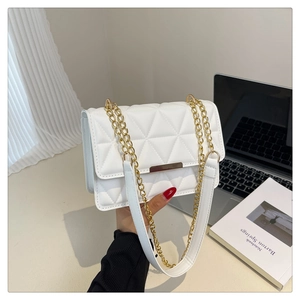 Detail of white quilted crossbody bag with golden metal trim and chain strap texture