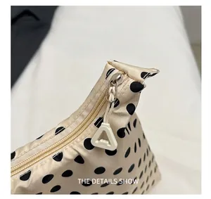 Détail de la fermeture éclair avec tirette triangle sur le sac à pois beige