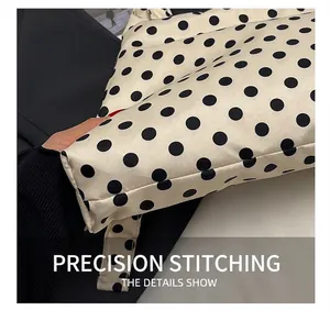 Gros plan détaillé des coutures précises sur un sac cabas en toile beige à pois noirs