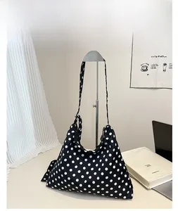 Détail du grand sac à bandoulière noir avec motif à pois blancs et design spacieux