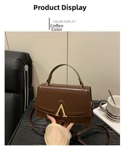 Détail d'un sac bandoulière en cuir marron brillant avec fermoir en V doré élégant