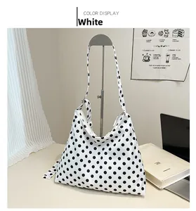 Vue détaillée du sac cabas blanc à pois avec bandoulière large sur support d'exposition