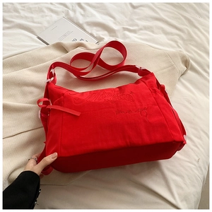 Detailed view of red canvas tote with premium embroidery and wide adjustable strap