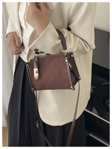 Sac bandoulière en daim marron avec motif matelassé porté par un mannequin