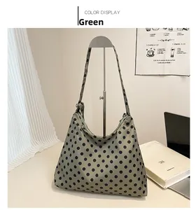 Détail d'un sac à bandoulière vert à pois noirs dans une ambiance urbaine chic