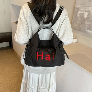 Black nylon commuter backpack with red Hai embroidery and adjustable wide straps