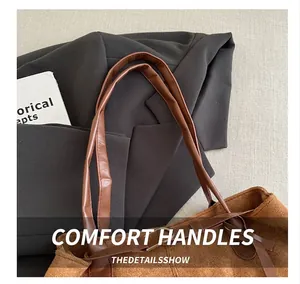 Detail view of the brown faux suede tote bag featuring reinforced durable faux leather handles