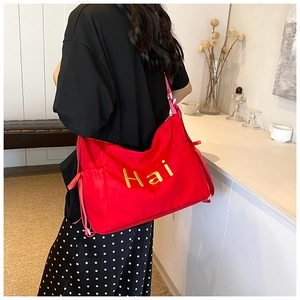 Vue détaillée du sac cabas en toile rouge avec broderie Hai dorée et cordon de serrage