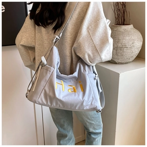 Détail macro d'un sac en nylon bleu clair avec lettres Hai brodées en jaune et sangle