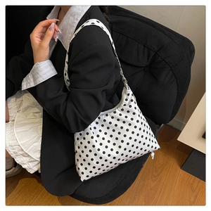 Détail d'un sac à bandoulière à pois stylé porté avec une tenue monochrome chic