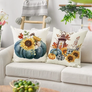 Detail of two autumn pumpkin and maple leaf throw pillow covers on a cozy sofa