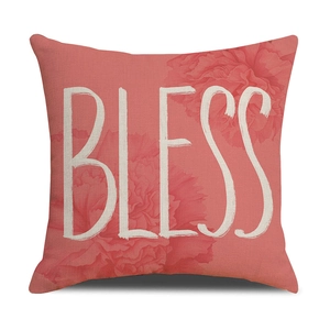Detail of coral linen cushion cover with white BLESS text and floral pattern