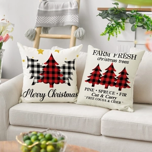 Close-up of two Christmas linen pillow covers with red plaid tree designs on a sofa