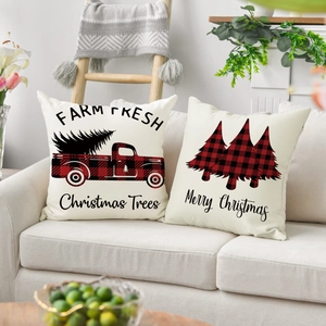 Detail of Christmas pillow covers featuring buffalo plaid trucks and festive trees on a sofa