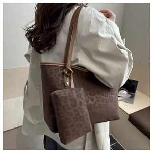Detail of a large leopard print tote bag with matching accessory pouch and leather straps