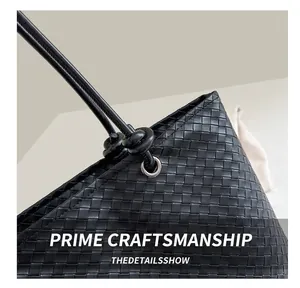 Close-up of woven leather texture on black tote bag with slender strap details