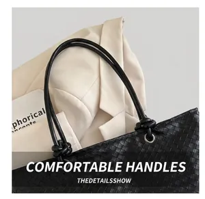 Detail of hand-woven black tote bag featuring knotted handles and metal eyelet accents