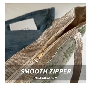 Detail shot of smooth metal zipper closure on nylon tote bag with green bamboo leaf pattern
